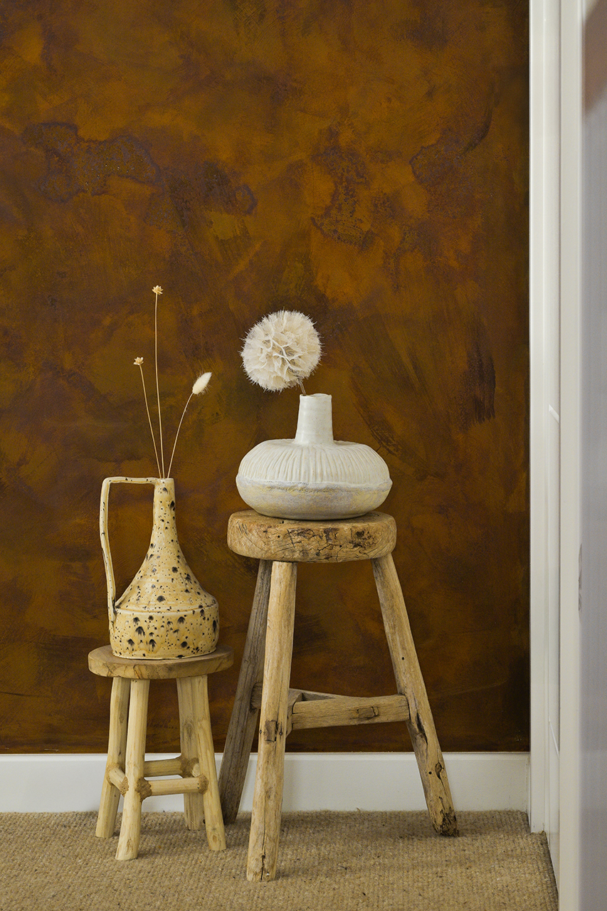 interior design image of stalls and vases with dried flowers in front of rust paint wall